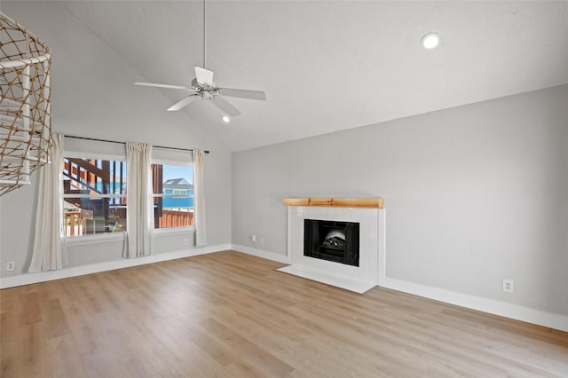 unfurnished living room featuring wood finished floors, baseboards, high vaulted ceiling, a fireplace, and ceiling fan