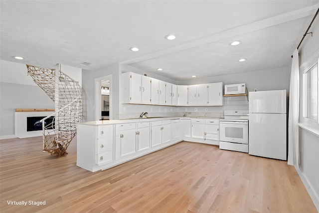 kitchen with light wood-type flooring, light countertops, white appliances, white cabinetry, and a sink