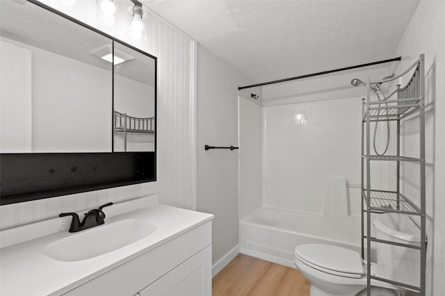 full bathroom with vanity, a textured ceiling, wood finished floors, shower / washtub combination, and toilet