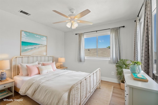 bedroom with visible vents, light wood-style flooring, a ceiling fan, and baseboards