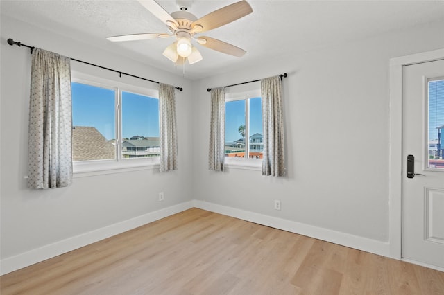 empty room featuring baseboards, wood finished floors, and a ceiling fan