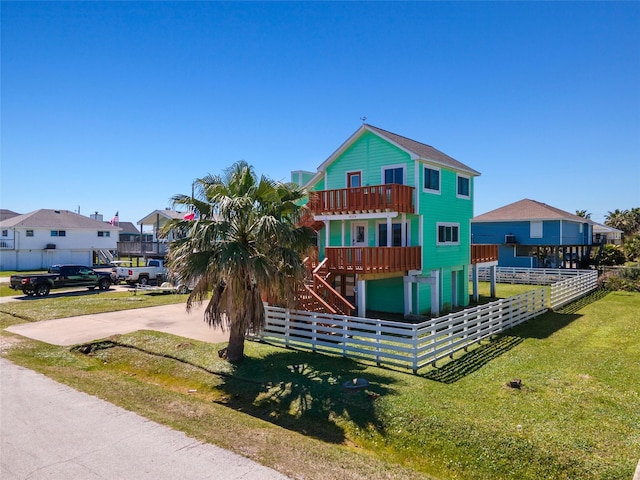 view of front of property featuring a fenced front yard, a residential view, a balcony, and a front lawn