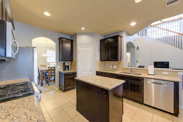 kitchen featuring visible vents, a kitchen island, stainless steel appliances, arched walkways, and dark brown cabinetry