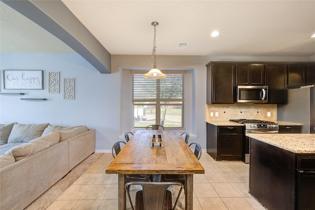 kitchen featuring light tile patterned floors, open floor plan, backsplash, and appliances with stainless steel finishes