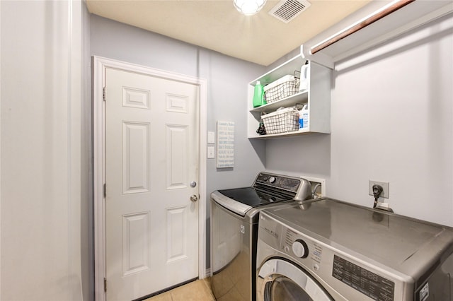 clothes washing area featuring light tile patterned floors, visible vents, independent washer and dryer, and laundry area