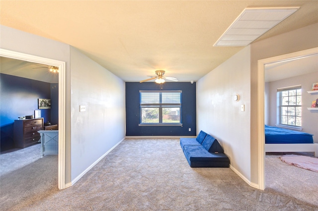 living area featuring visible vents, carpet flooring, baseboards, and ceiling fan