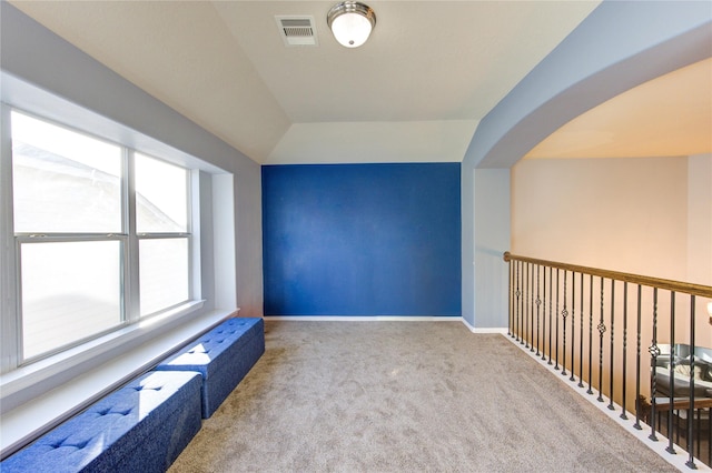 interior space with carpet flooring, baseboards, visible vents, and arched walkways