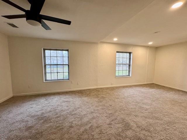 unfurnished room featuring visible vents, a healthy amount of sunlight, a ceiling fan, and carpet floors