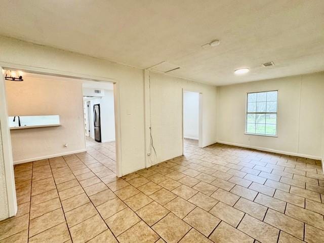 spare room featuring light tile patterned floors and baseboards