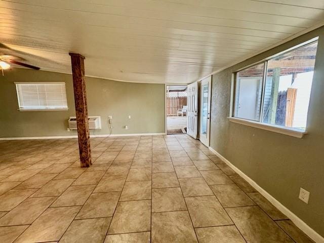 tiled empty room featuring baseboards, an AC wall unit, and a ceiling fan