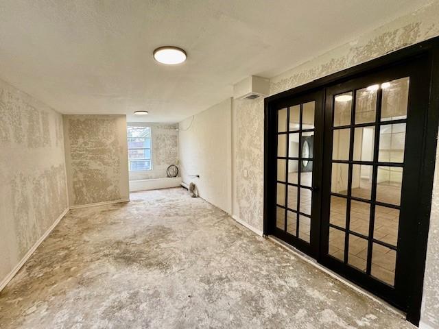 empty room with french doors and unfinished concrete flooring