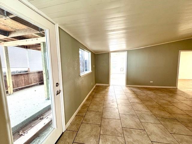 empty room featuring baseboards, wood ceiling, and tile patterned flooring