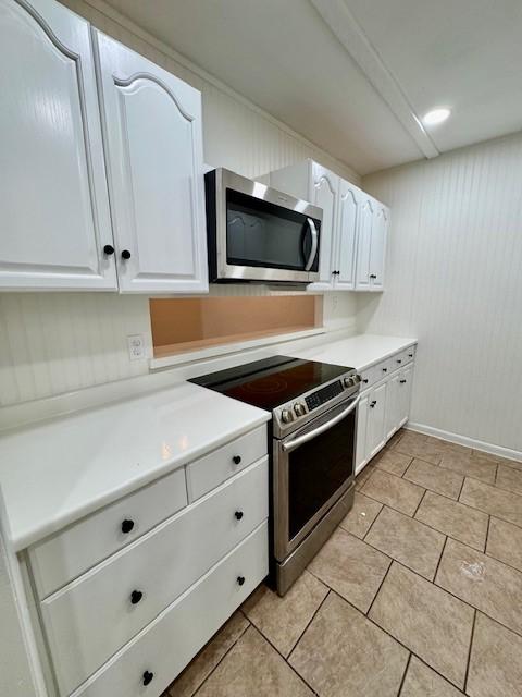 kitchen with light tile patterned floors, white cabinets, appliances with stainless steel finishes, and light countertops