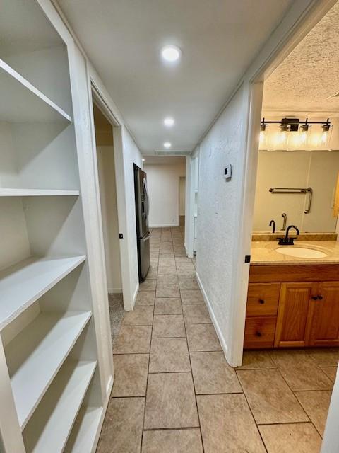 hall with light tile patterned floors, recessed lighting, and a sink