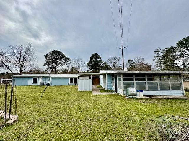 back of property featuring a lawn and a sunroom