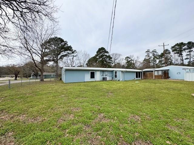 rear view of property featuring a lawn and fence