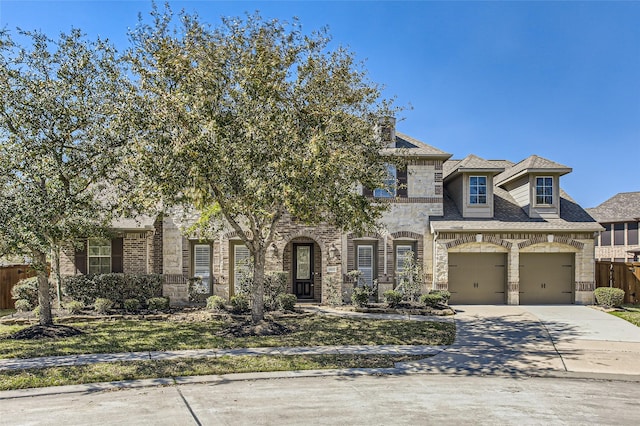 view of front of property featuring fence, stone siding, driveway, and a shingled roof