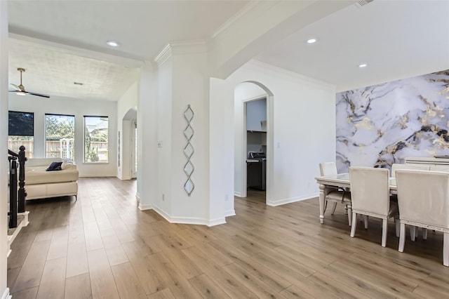 dining room featuring arched walkways, ornamental molding, baseboards, and wood finished floors