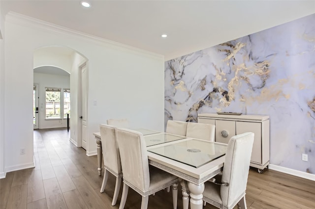 dining area with wood finished floors, baseboards, recessed lighting, arched walkways, and crown molding