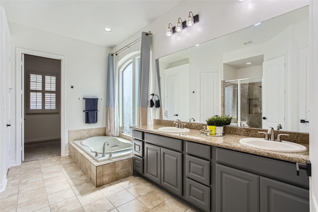 bathroom with tile patterned floors, a bath, a stall shower, and a sink