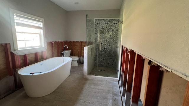 bathroom with a shower stall, a wainscoted wall, toilet, a soaking tub, and tile walls