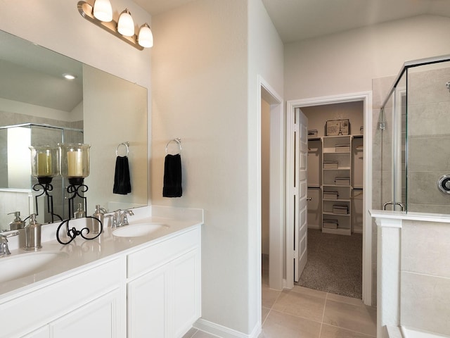 bathroom featuring a spacious closet, a stall shower, and a sink