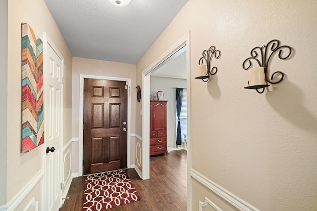 foyer entrance with a textured ceiling and dark wood finished floors