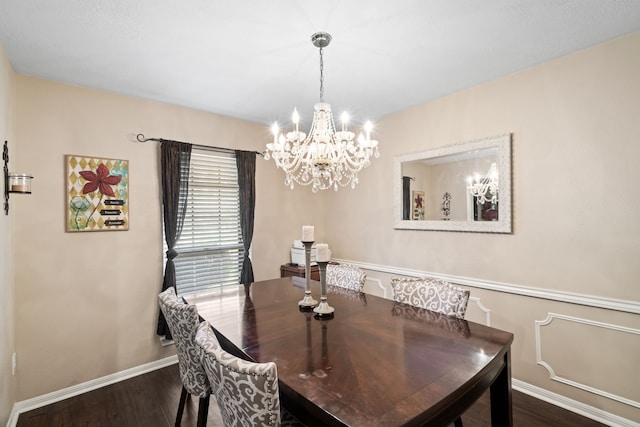 dining room with dark wood-type flooring, a notable chandelier, and baseboards