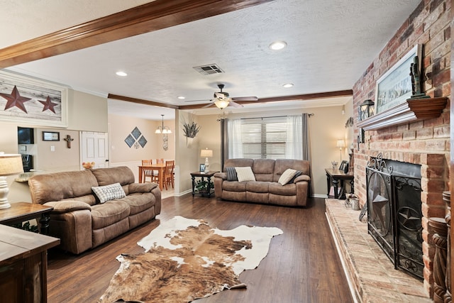 living area featuring visible vents, a fireplace, wood-type flooring, a textured ceiling, and crown molding