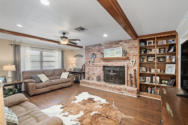 living room featuring visible vents, a brick fireplace, crown molding, beamed ceiling, and wood finished floors