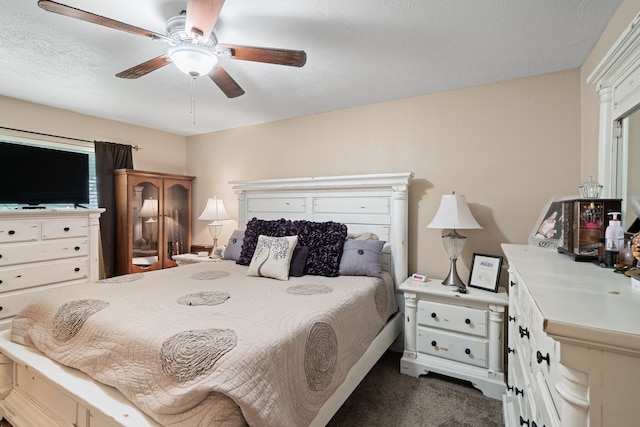 bedroom featuring a textured ceiling, ceiling fan, and dark colored carpet