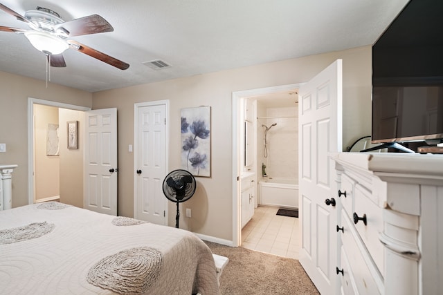 bedroom featuring a ceiling fan, visible vents, baseboards, ensuite bath, and light colored carpet