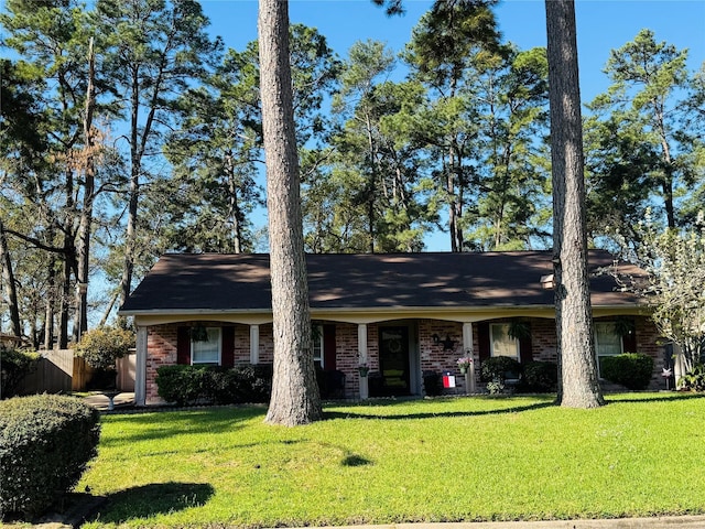 ranch-style home with brick siding, a front lawn, and fence