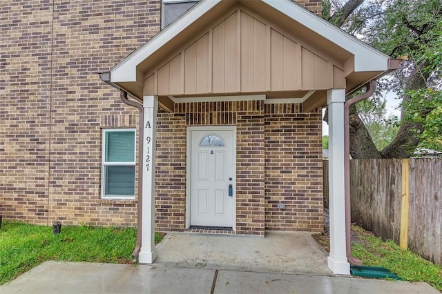 property entrance featuring fence and brick siding