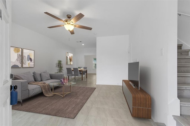 living area with light tile patterned floors, stairway, and ceiling fan