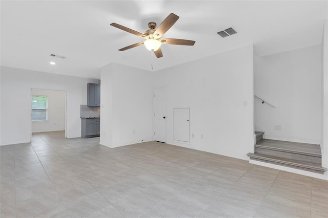 unfurnished living room with visible vents, stairs, and ceiling fan