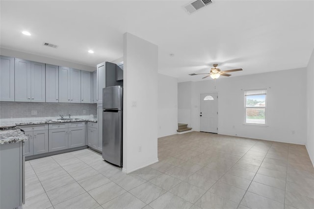 kitchen with visible vents, freestanding refrigerator, open floor plan, and decorative backsplash