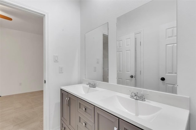 bathroom with double vanity, baseboards, and a sink