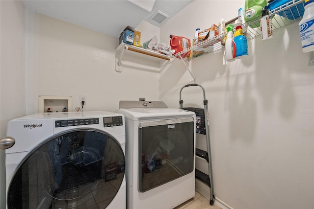 laundry area featuring baseboards, visible vents, washing machine and clothes dryer, laundry area, and light tile patterned flooring