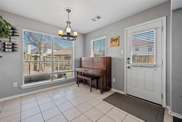 foyer entrance featuring light tile patterned floors, visible vents, a healthy amount of sunlight, and an inviting chandelier