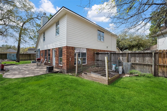 rear view of house with a yard, a patio, brick siding, and a chimney