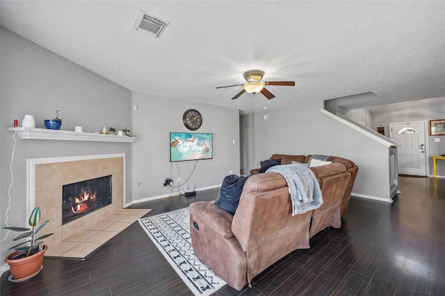 living area featuring a ceiling fan, wood finished floors, visible vents, a fireplace, and a textured ceiling