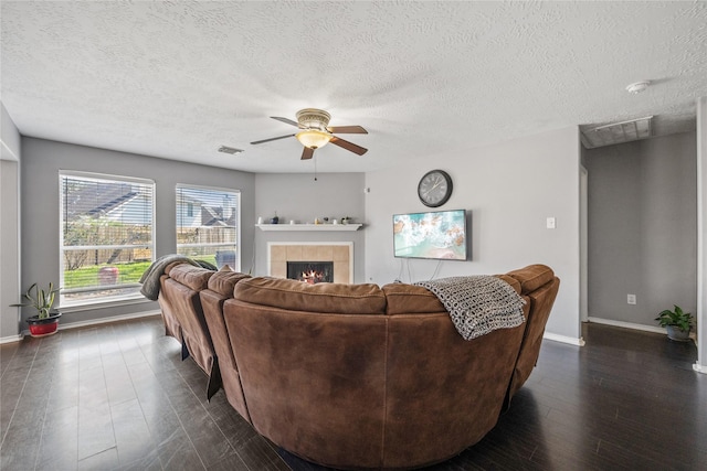 living area featuring dark wood-type flooring, a fireplace, visible vents, and baseboards