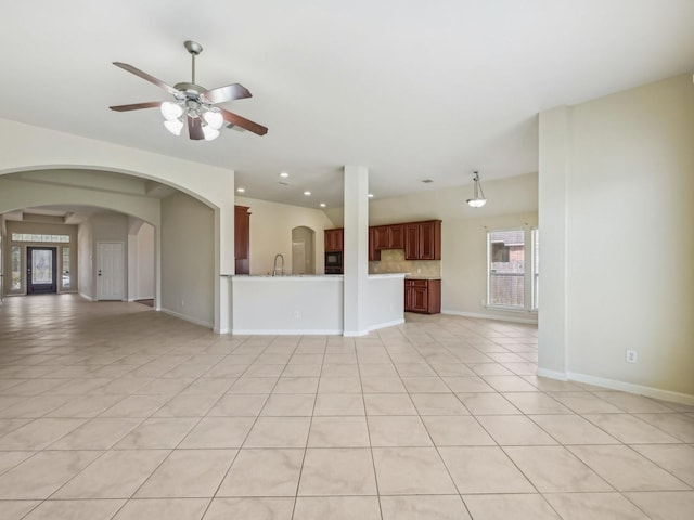 unfurnished living room featuring a sink, baseboards, arched walkways, and recessed lighting