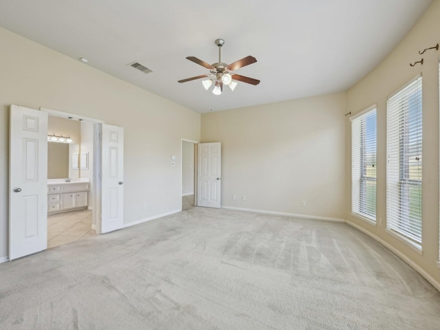 unfurnished bedroom featuring visible vents, light carpet, connected bathroom, baseboards, and ceiling fan