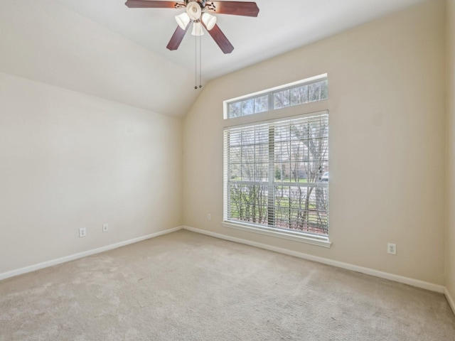 empty room with vaulted ceiling, carpet flooring, baseboards, and ceiling fan