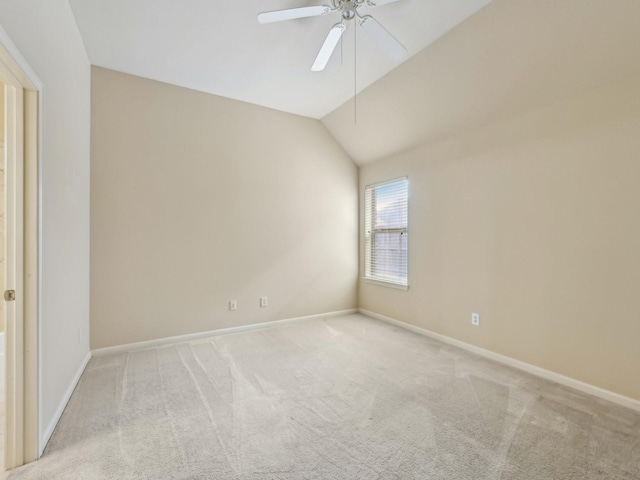 empty room with vaulted ceiling, carpet flooring, a ceiling fan, and baseboards