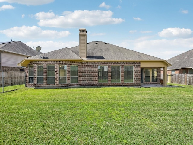 back of house featuring a fenced backyard, brick siding, and a lawn