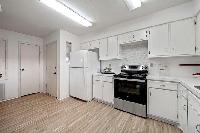 kitchen with light wood-type flooring, stainless steel electric stove, freestanding refrigerator, white cabinets, and light countertops