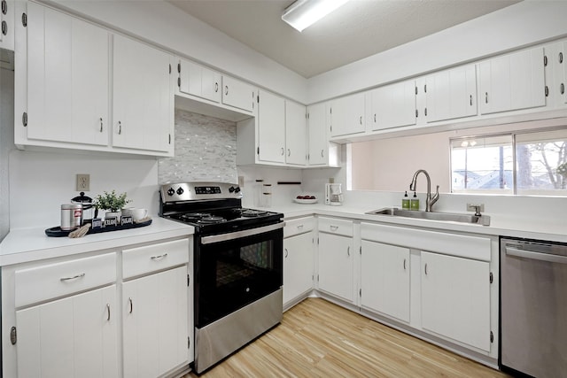 kitchen featuring light wood finished floors, stainless steel appliances, light countertops, and a sink